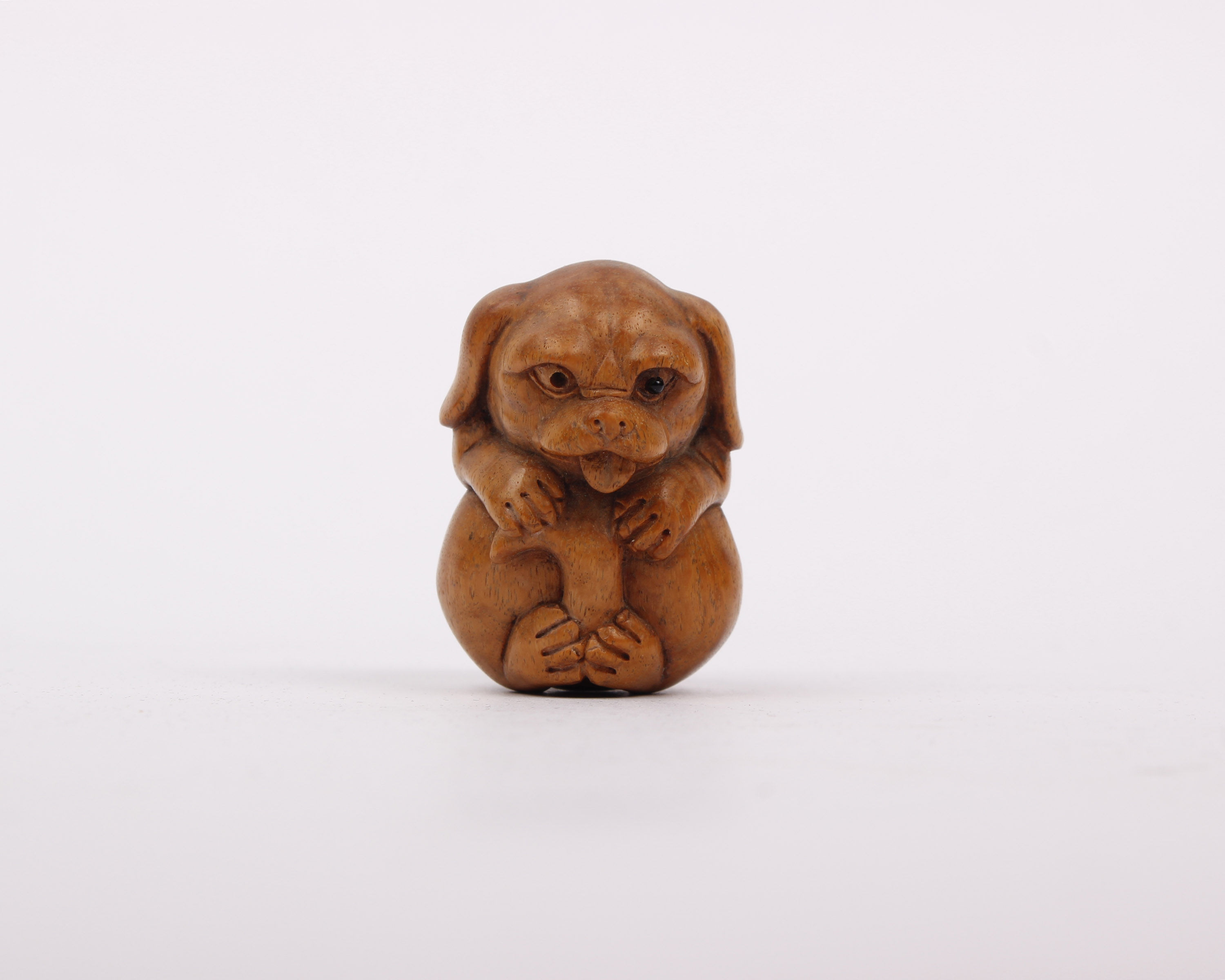 A small wooden carved Netsuke of a dog.