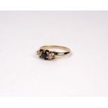 A 14k gold sapphire and diamond ring. Central round cut sapphire with single cut diamond accents.