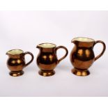 A set of three graduated 'Copper Lustre' glazed jugs marked Creigiau pottery, Cardiff, Wales
