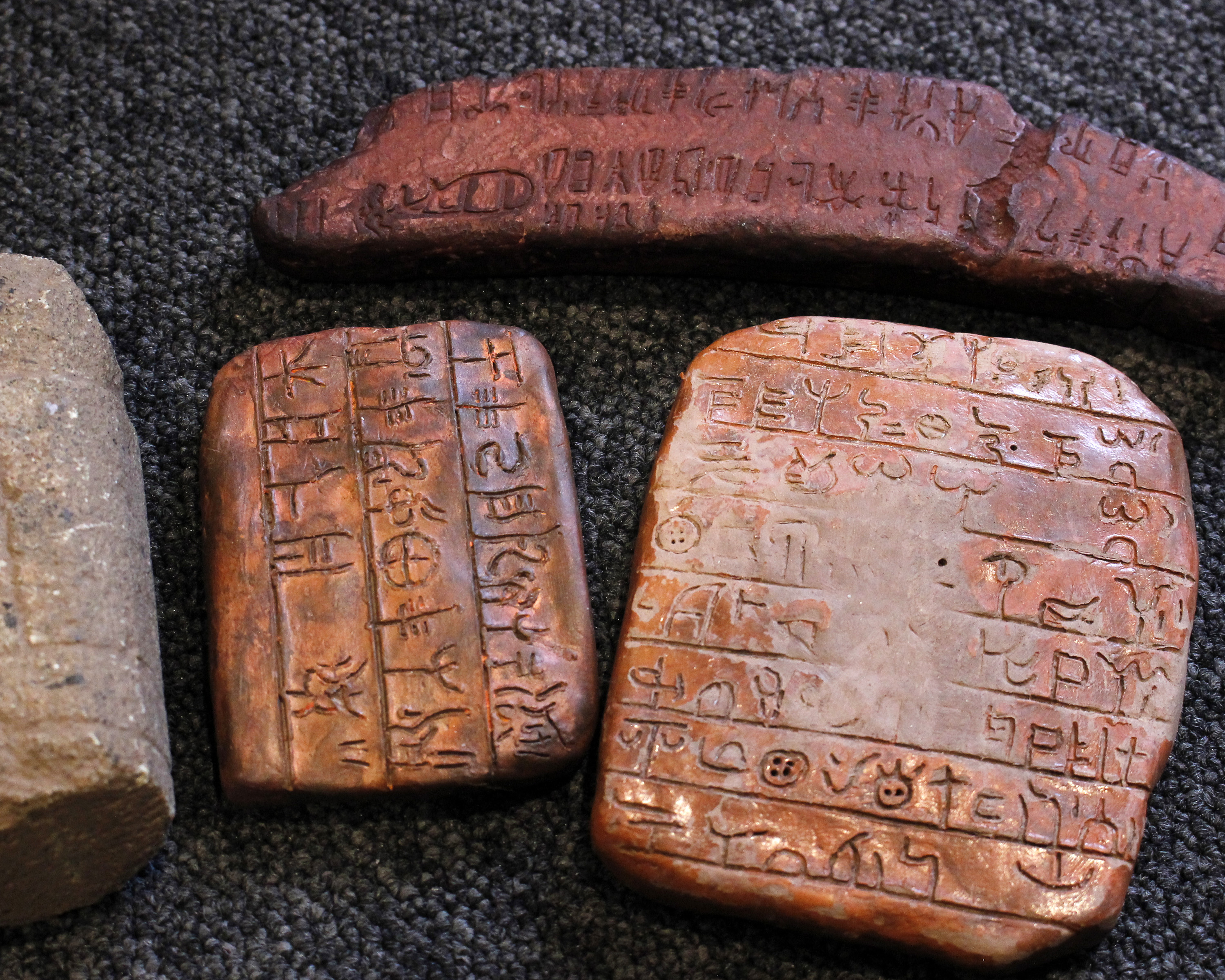 Three replica clay tablets depicting early writing forms, possible Scandinavian example, together