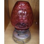 An Antique Metal Based Oil Lamp with Cranberry Glass Shade 43 cm high