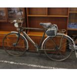 A vintage green framed men's Rayleigh bike with dynamo light, bicycle pump and rear rack carrier