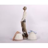 A Lladro porcelain figurine of Don Quixote with sword and armour, along with some books at his feet,