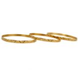 Three yellow metal bangles, with geometric bright cut design, stamped with Egyptian control marks
