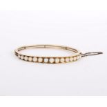 A gold coloured cultured pearl bangle, the hinged bangle set with cultured pearls, 5.7cm wide, 14.3g