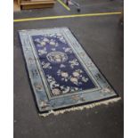 A turquoise rug with navy blue central panel with pink and white flowers Dimensions 178cm by 88.8cm