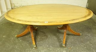 Walnut Coffee Table, Having an oval top, raised on two tripod pedestals, terminating on brass caps