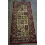 Persian Style Rug, Decorated with floral motifs on a green ground, label to reverse named