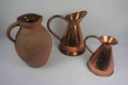 Two Graduated Copper Measuring Jugs, 22cm high, 30cm high, Also with a Terracotta Jug, (3)