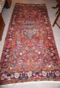 Persian Style Rug, Decorated with Geometric and Floral Medallions on a Red Ground, 303cm x 140cm