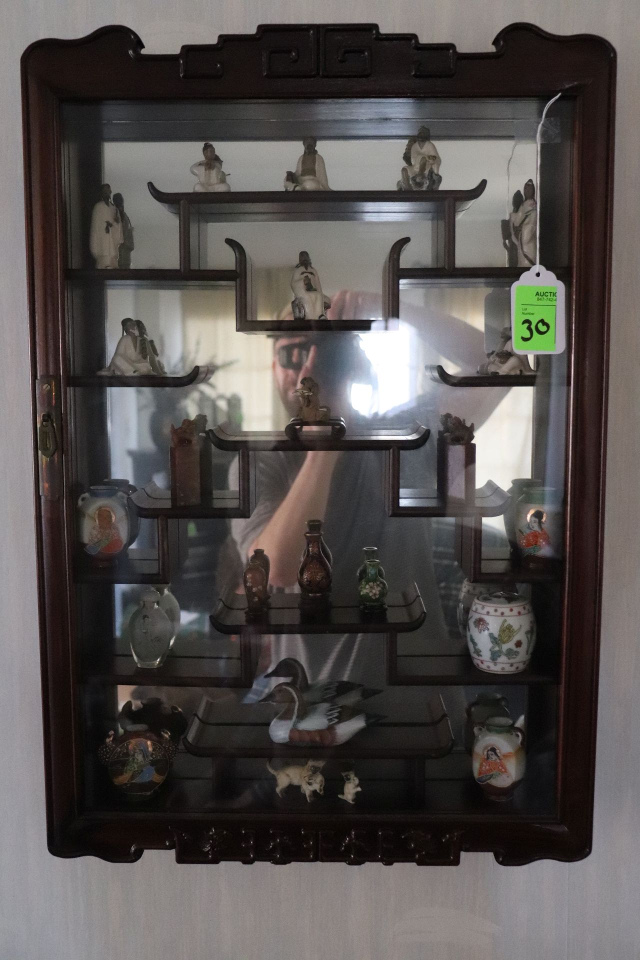 Curio cabinet with mirrored back and contents including bottles, figurines, and vessels