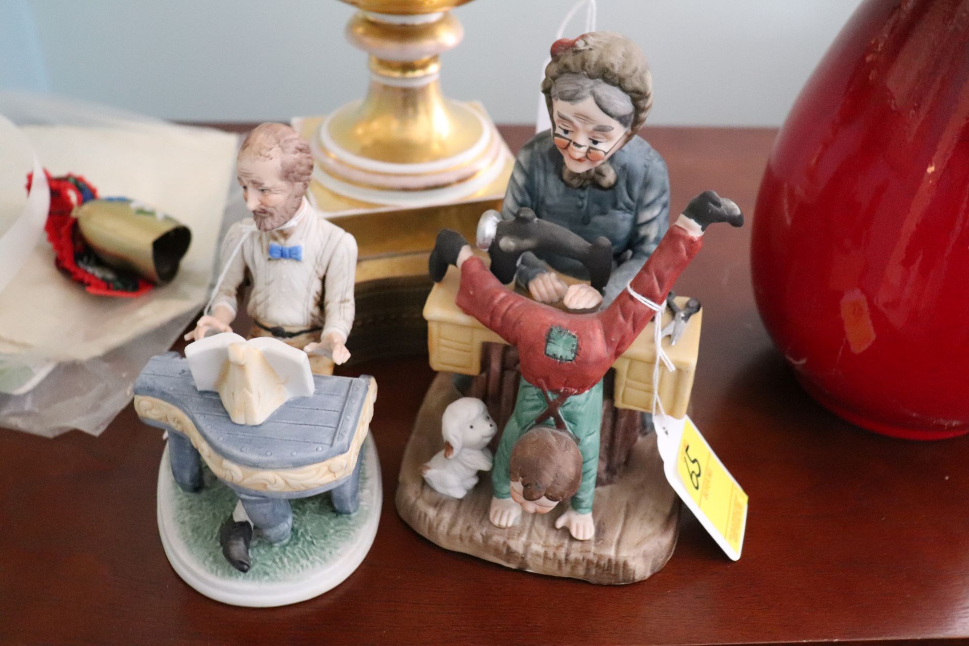 Two porcelain figures, one of a man playing piano and one of a grandmother sewing, height of tallest