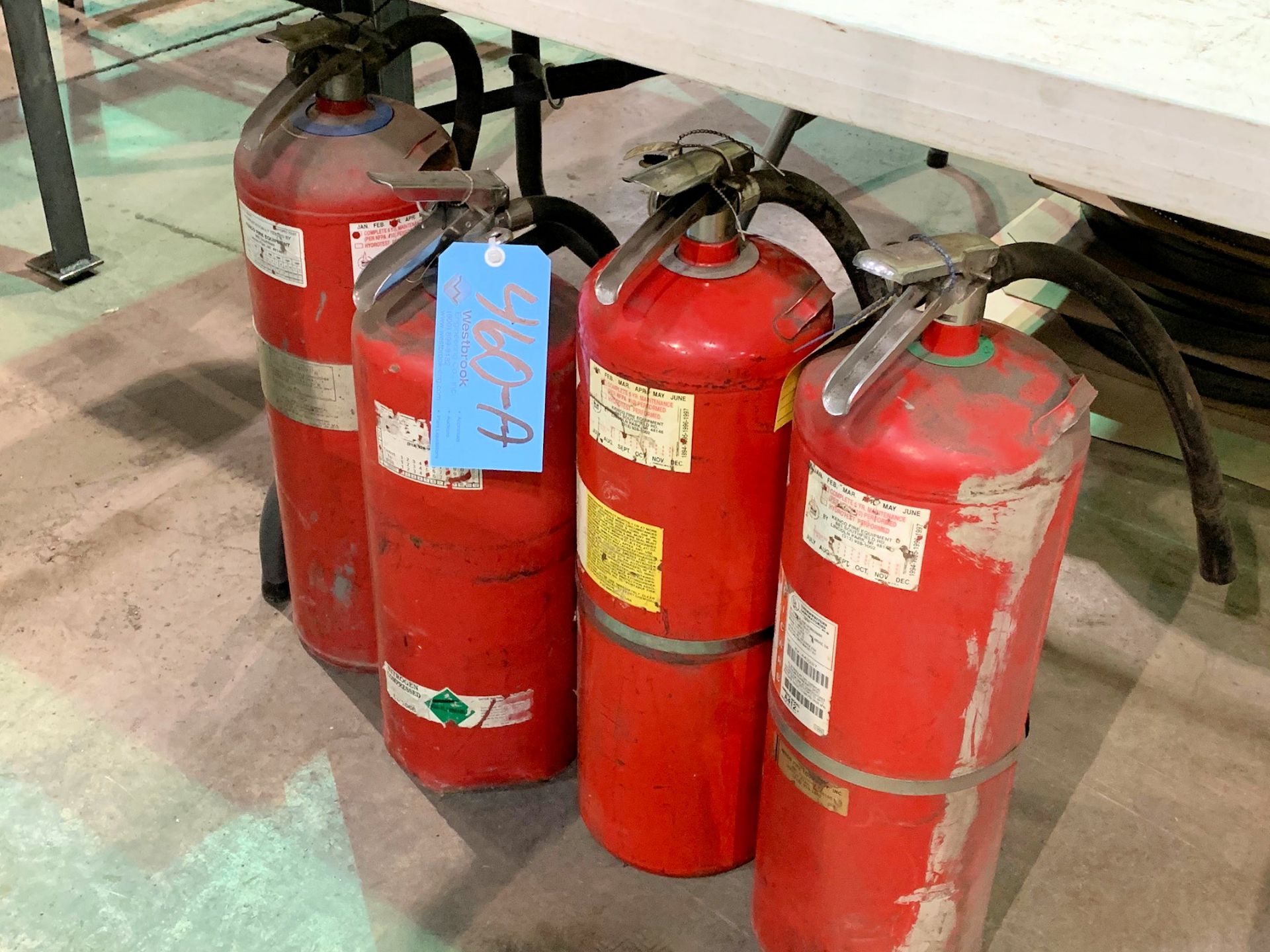 Lot-(4) Fire Extinguishers Under (1) Table