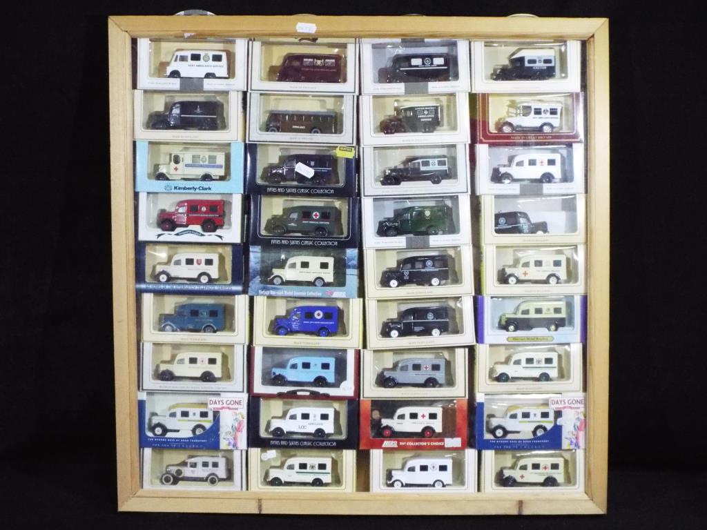 Lledo - 32 diecast model ambulances by Lledo contained within a wooden display cabinet measuring