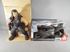 A DC Justice League Batmobile by Mattell FGG58 and a WWE action figure of Roman Reigns, both boxed.