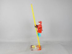Marx - An unboxed tinplate and plastic 'Climbing Fireman' by Marx. The toy is in Playworn condition.