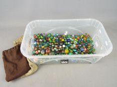 Marbles - A large collection of glass marbles in a variety of sizes in a plastic container which