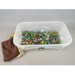 Marbles - A large collection of glass marbles in a variety of sizes in a plastic container which