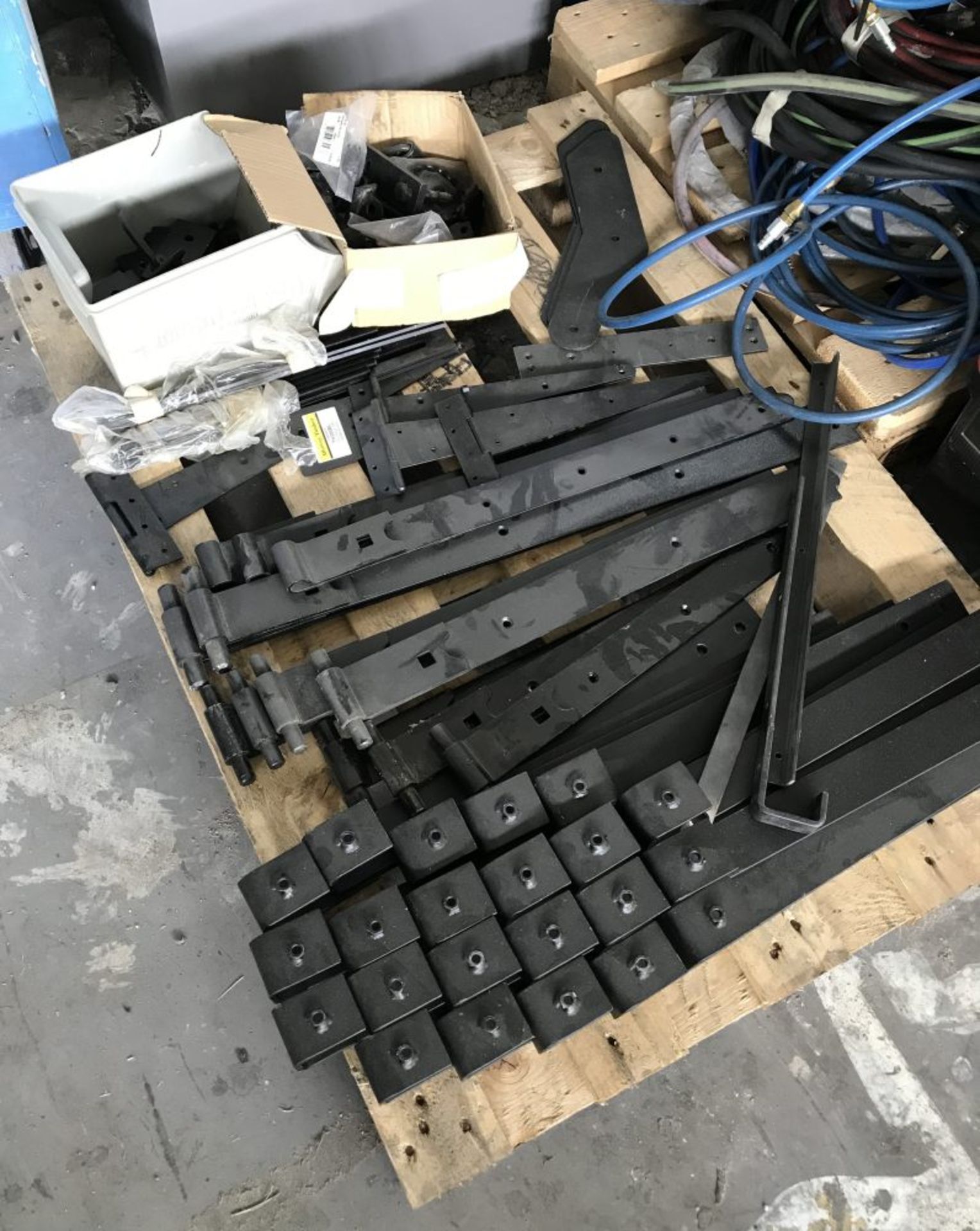 A pallet of black heavy duty hinges and other door furniture