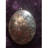 Large vintage silver locket, oval shape with foliage scroll work to cover and a plain silver back,