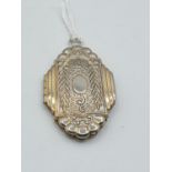 A white metal art deco style locket with gilt facings and original pictures