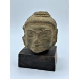 Bronze Buddhist head on wooden stand.