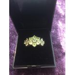 Stone set silver and peridot ring, having 15 stones forming a central flower to each side, size N