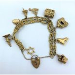 An ornate 9ct gold charm bracelet with 9 gold charms. Weighing 50.7g.