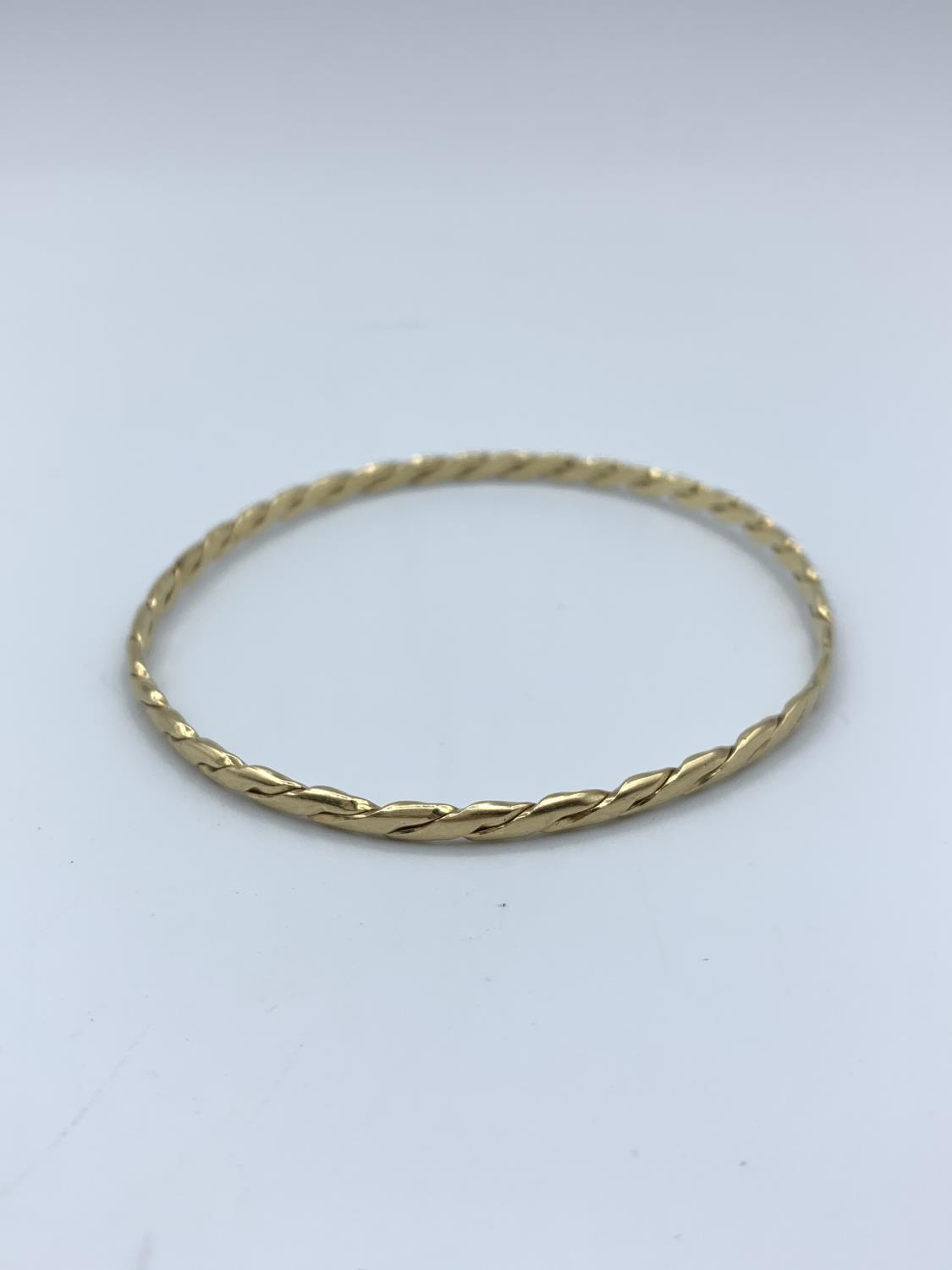 A yellow metal (tested as 9ct gold) twisted bangle, weight 9.5g approx