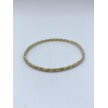 A yellow metal (tested as 9ct gold) twisted bangle, weight 9.5g approx