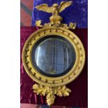 An impressive gilt early 19th C convex mirror having a large carved eagle looking over the