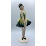 Elegant 1920 style porcelain figurine of a lady in a short green and yellow dress with hat. Numbered