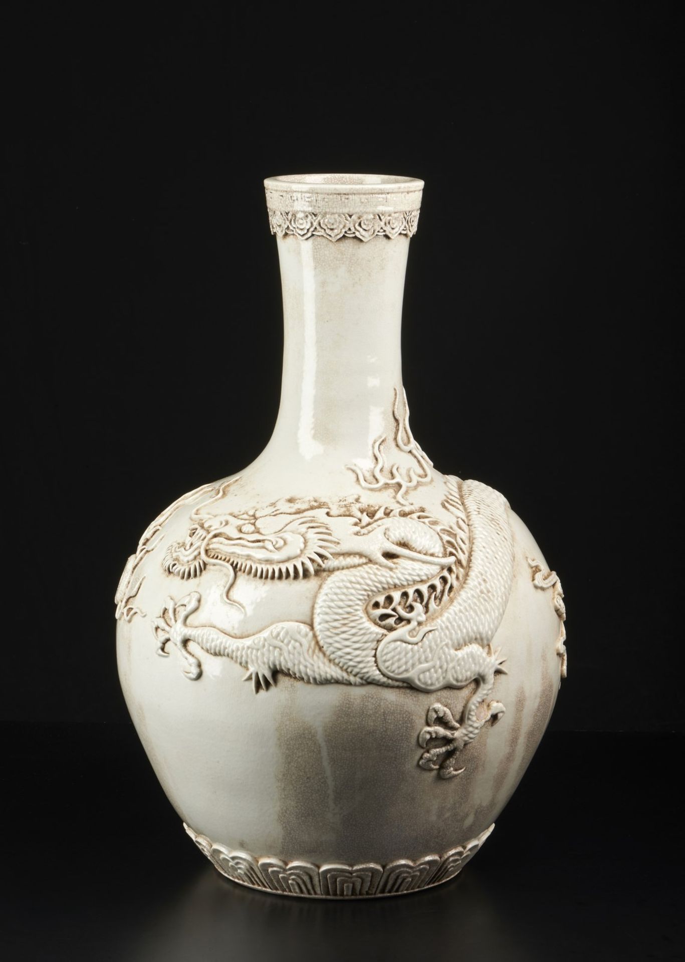 Arte Cinese A large white porcelain vase with applied decoration depicting a dragon chasing the fla