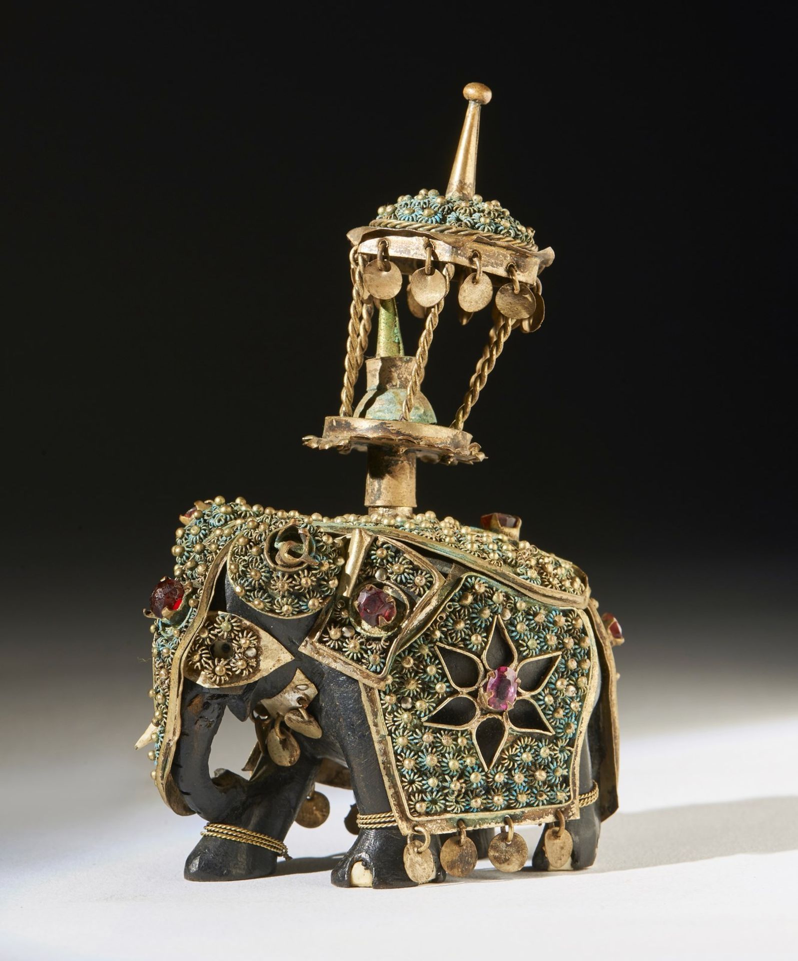 Arte Indiana An ebony elephant shaped chess piece partially coated with metal and garnets India, 19