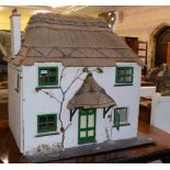 A two story dolls house, with a thatched roof and entrance, with various furnishings, 102 cm wide