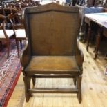 A 17th/18th century oak wingback chair, with a lancet shaped top, a curved back, on solid end