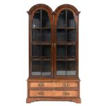 A George I style walnut bookcase on chest, having a pair of dome top bar glazed doors, above two