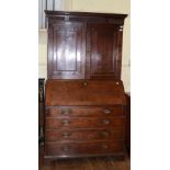 A George III oak bureau bookcase, having a pair of panel doors inlaid stars, above a bureau section,