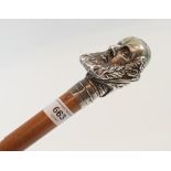 A walking cane, having a silver coloured metal handle in the form of the head of a religious figure,