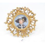 A porcelain dish, decorated a young man, in a Florentine carved giltwood frame, 21 cm diameter