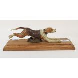 A painted bronze paperclip, in the form of a running dog, on an oak base, 28 cm wide Modern