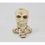 A bone candlestick, carved in the form of four skulls, 7 cm high Modern