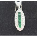 An Art Deco style 18ct white gold, emerald and diamond pendant, of navette form, the emeralds