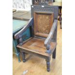 An oak wainscot armchair, the panel back inlaid with a vase of flowers, on turned front legs