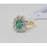 An 18ct yellow gold, emerald and diamond cluster ring, the oval cut emerald of approx. 1.60ct within