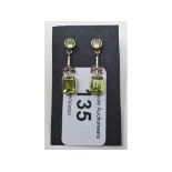 A pair of 9ct gold and emerald cut peridot drop earrings