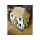 A two story dolls house, with a thatched roof and entrance, with various furnishings, 102 cm wide