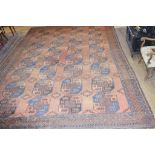 An Afghan style carpet, with four rows of eight medallions, on a red/brown ground, 465 x 306 cm