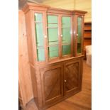 A Victorian pitch pine cabinet on cupboard, having two pairs of glazed doors above a pair of panel