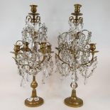 A pair of brass and cut glass candelabra, with upper nozzle above four scroll branches, each hung